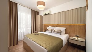 A hotel room with a large bed, a bedside table with a lamp, an air conditioning unit, and a window with curtains. - Marmada Suites (Istanbul)