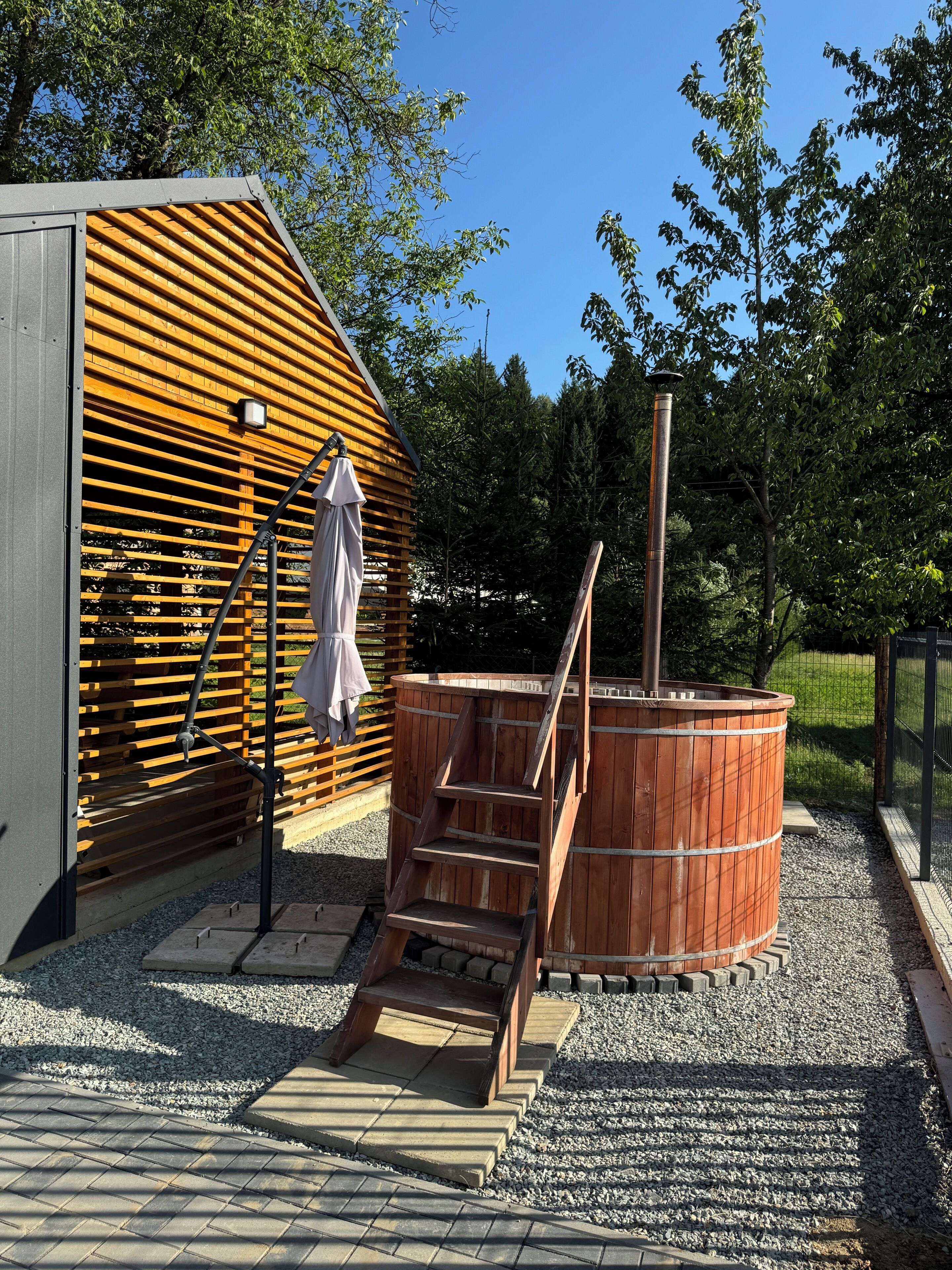 A wooden sauna structure with a metal staircase, a wooden bench, and a metal heater.