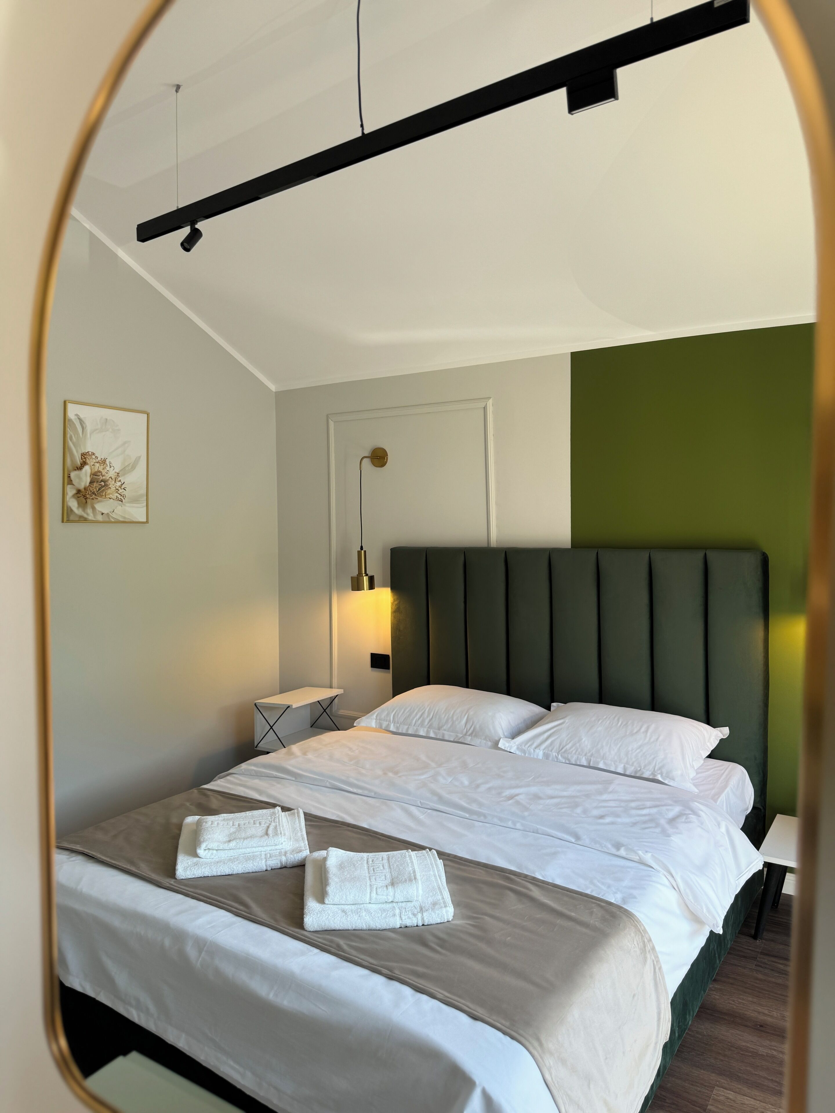 A hotel room with a bed, a bedside table, a lamp, and a wall-mounted light fixture.