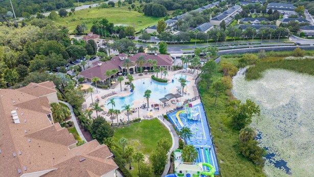 An aerial view of a resort with a swimming pool, water slides, and a large lawn area. - 3-bedroom townhome in delightful Kissimmee with WiFi, AC, and Cable TV. (Kissimmee)