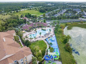 Eine Vogelperspektive zeigt ein Resort mit Schwimmbad, Wasserrutschen und einer großen Rasenfläche.