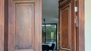 A wooden double door with a 'WELCOME' mat at the entrance, leading to a dining area with a table and chairs.
