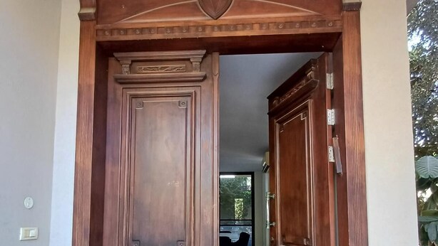 A wooden double door with a 'WELCOME' mat in front.
