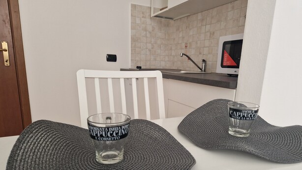 A dining table with two glass candle holders and a white chair.