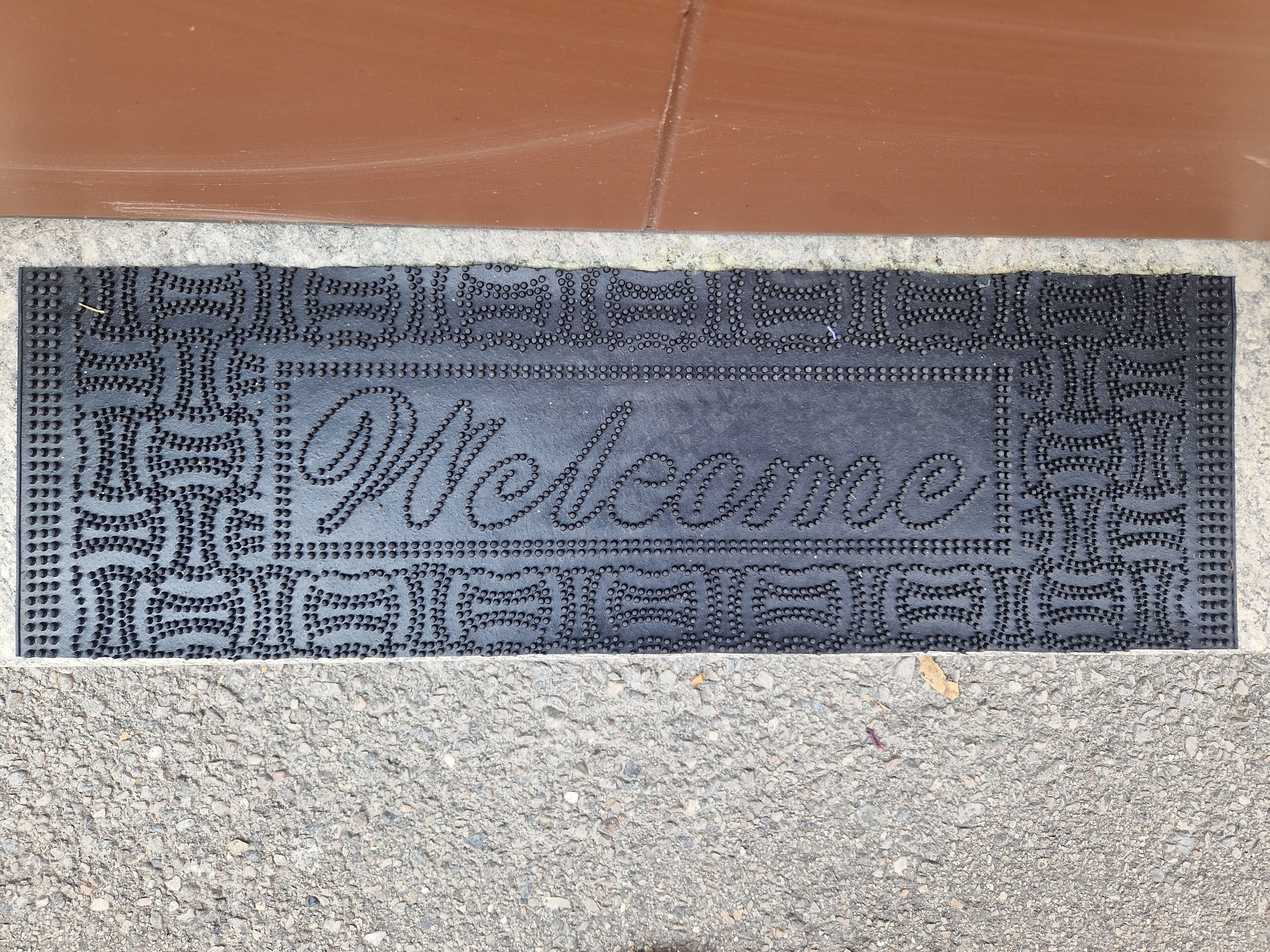 Un felpudo con un diseño decorativo y la palabra 'Welcome' grabada.