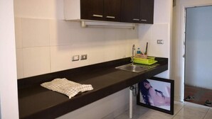 A kitchen with dark cabinets, a sink, and a countertop. - Jomtien Hill Resort Pratamnak 107 (Pattaya)