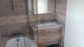 Une salle de bain moderne avec une baignoire, un meuble-lavabo avec un espace vitré et une zone de douche.