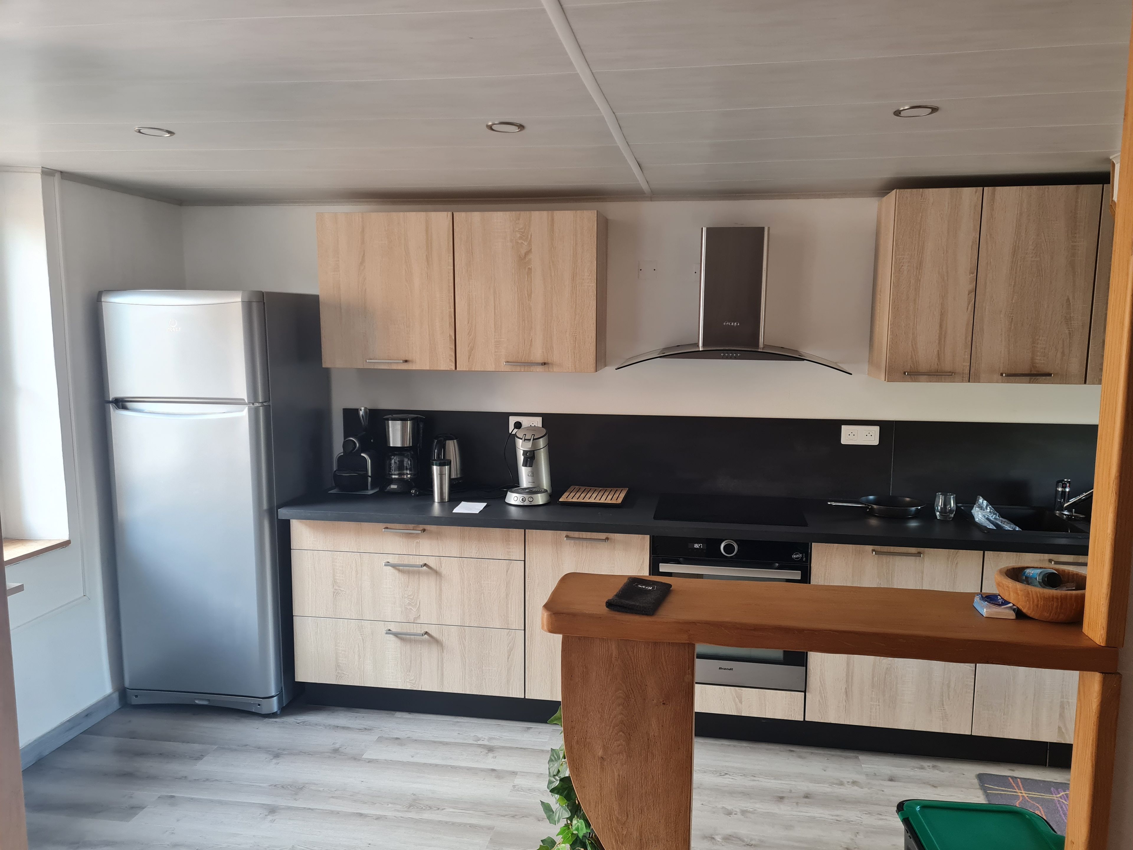 Eine moderne Küche mit Holzschränken, einem Edelstahlkühlschrank und einem eingebauten Ofen.