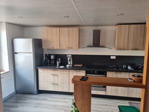 Una cocina moderna con armarios de madera, un refrigerador de acero inoxidable y un horno empotrado.
