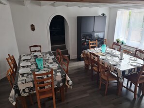 Uma sala de jantar com uma mesa grande posta para seis pessoas, rodeada por cadeiras de madeira.