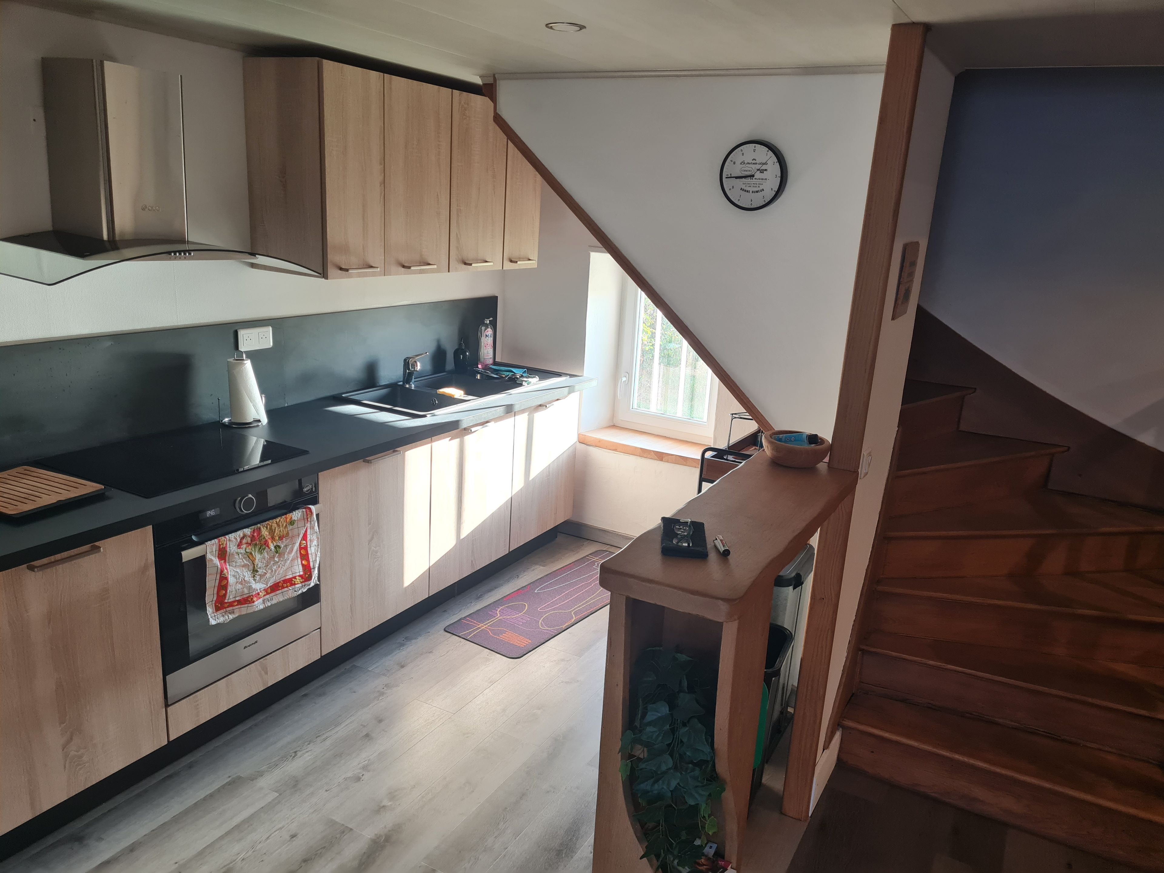 Eine moderne Küche mit Holzausstattung, einer schwarzen Arbeitsplatte und einem eingebauten Backofen.
