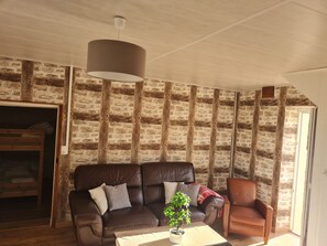 Uma sala de estar com um sofá de couro marrom, uma mesa de centro de madeira e um vaso com planta.