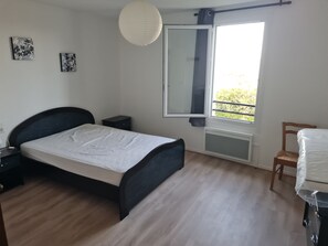 Una camera da letto con un letto, comodini, una finestra vista e un termosifone.
