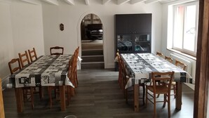 A dining area with a long table and chairs, a black cabinet, and a view of a staircase leading to another room.