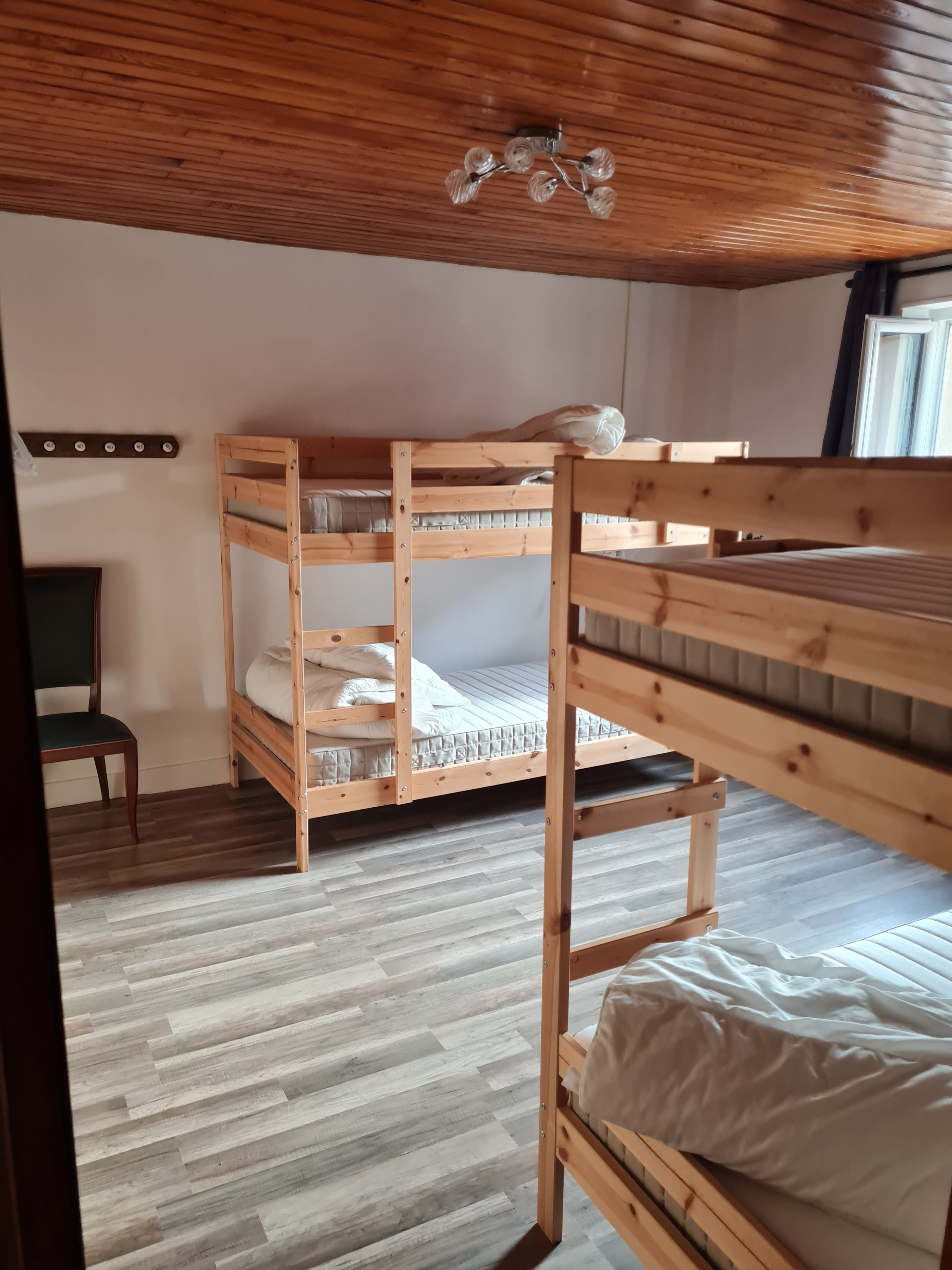 Une chambre avec un lit superposé, un plafond en bois et une petite table.