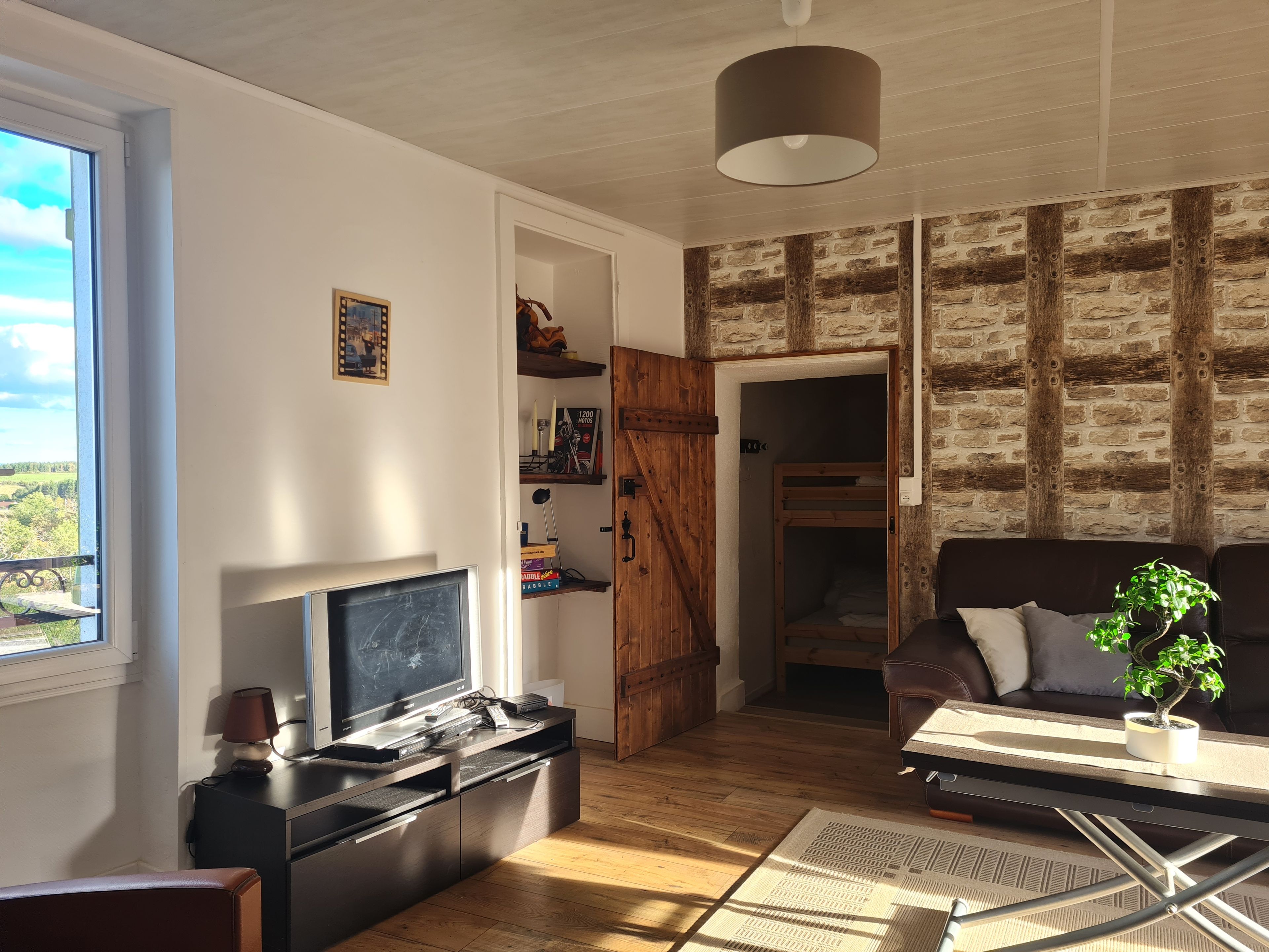 Un salon équipé d’un téléviseur, de meubles en bois, d’un canapé et offrant une vue sur l’extérieur.