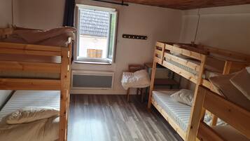 Ein Schlafraum mit Etagenbett, Fenster, Holzboden und Heizkörper.