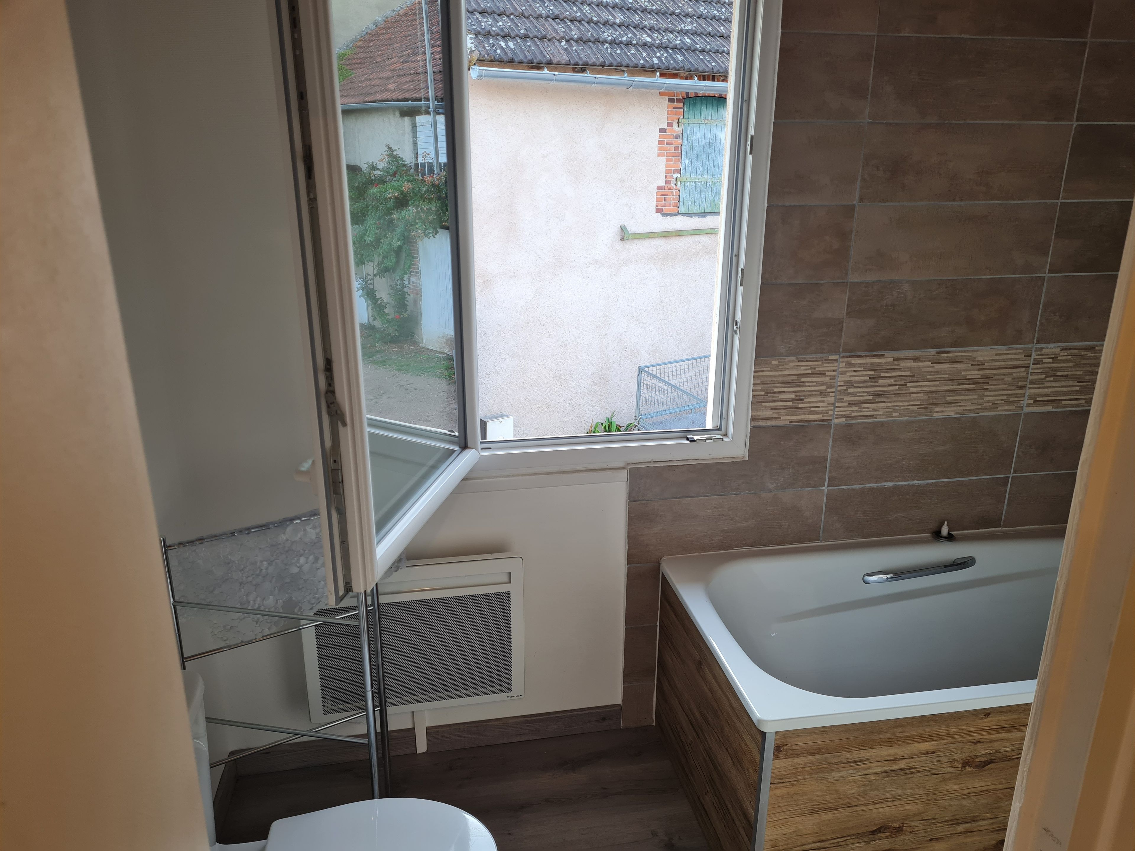 A bathroom with a bathtub, a window, and a radiator.