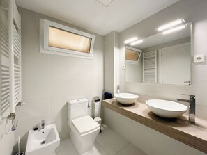 Une salle de bain moderne équipée de toilettes, d’un bidet et de deux lavabos.