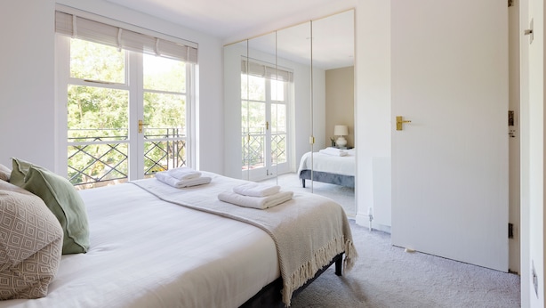 Une chambre avec un grand lit, un miroir et une vue sur un balcon.