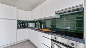 A modern kitchen with white cabinets, a black countertop, and a green-tiled backsplash. - Central & luminous apartment in Antwerp, foreseen with all comforts (Antwerpen)
