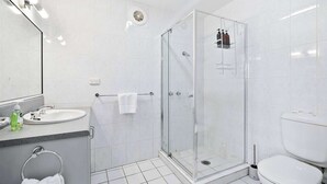 A modern bathroom with a glass-enclosed shower, a sink with a mirror, and a toilet. - 'Hillside Studio' self-contained with City Views. (Howrah)