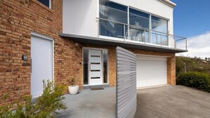 A modern two-story house with a brick facade, a white garage door, and a balcony with glass railings. - 'Hillside Studio' self-contained with City Views. (Howrah)