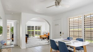 Zona pranzo con tavolo bianco, sedie blu e ventilatore a soffitto.