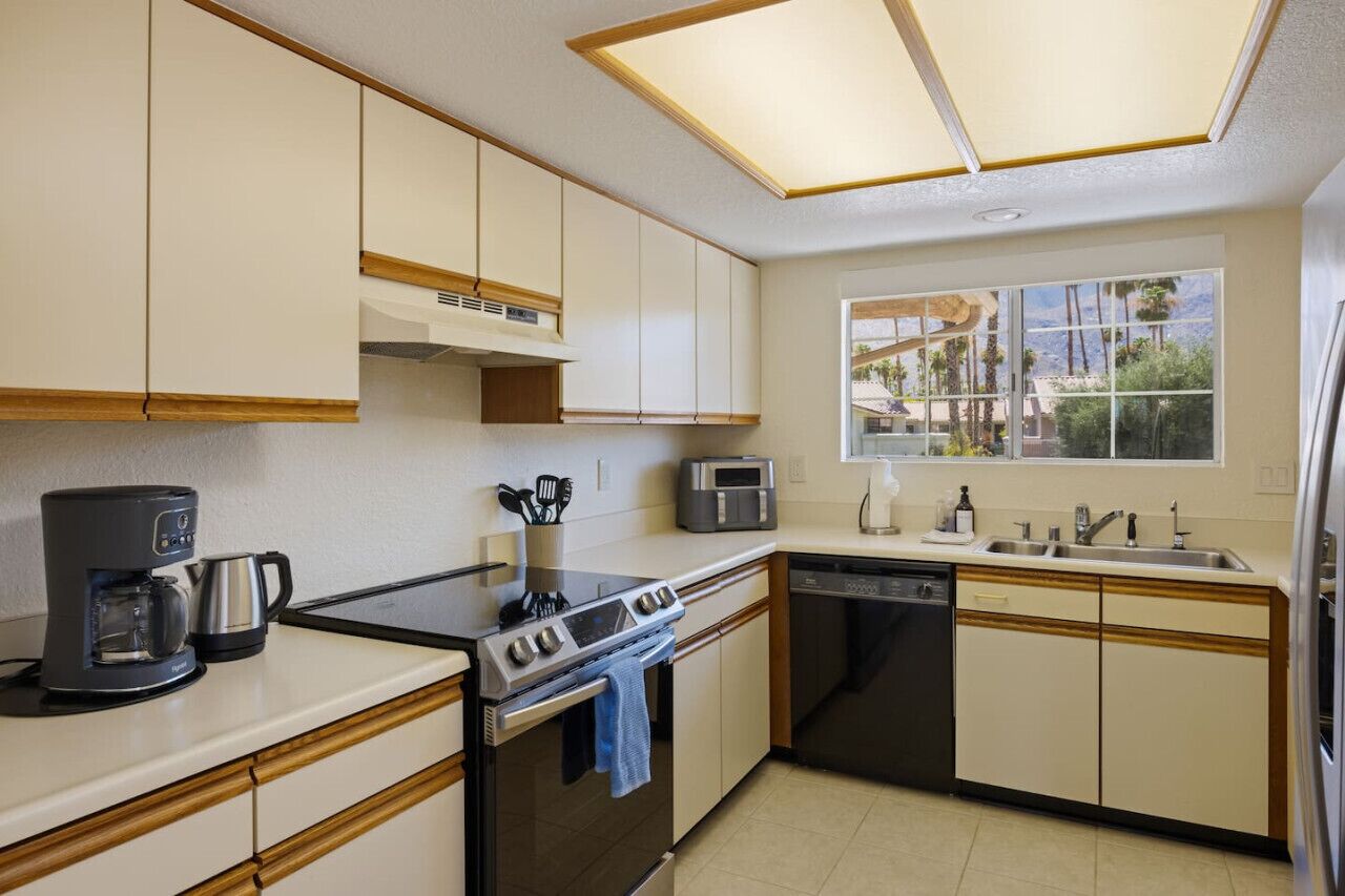A compact kitchen with a stove, oven, coffee maker, microwave, and dishwasher.