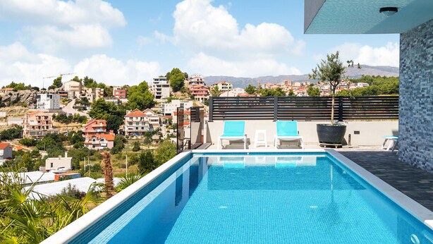A rooftop infinity pool with two lounge chairs, a potted plant, and a view of a hillside town. - Awesome apartment in Podstrana with WiFi (Podstrana)