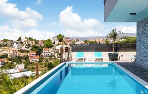 A rooftop infinity pool with two lounge chairs, a potted plant, and a view of a hillside town. - Awesome apartment in Podstrana with WiFi (Podstrana)