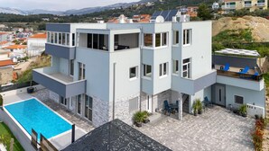A modern multi-story building with a rooftop pool, outdoor seating, and a view of the surrounding landscape. - Awesome apartment in Podstrana with WiFi (Podstrana)