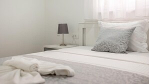 A neatly made bed with a grey patterned pillow and white linens, a bedside lamp, and a white nightstand. - Awesome apartment in Podstrana with WiFi (Podstrana)