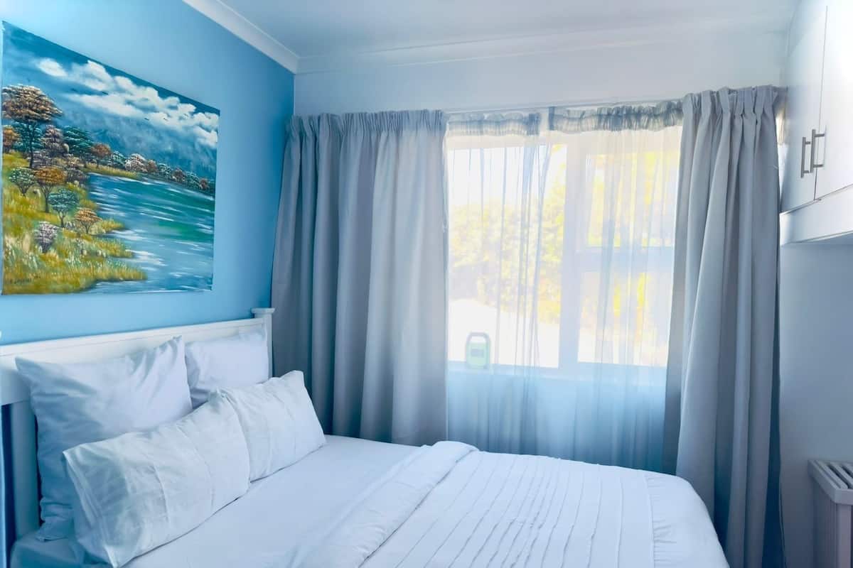 Ein Schlafzimmer mit einem Bett, einem Gemälde und einem Fenster mit Vorhängen.