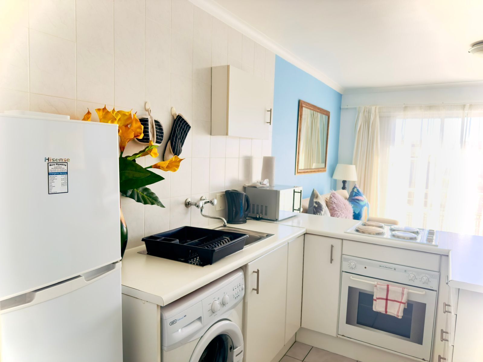 Una cocina compacta equipada con lavadora, refrigerador, microondas y horno pequeño.