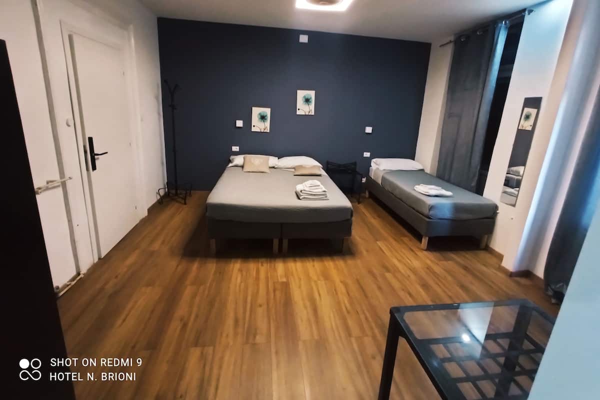 A hotel room with two beds, a small table, and a ceiling light.