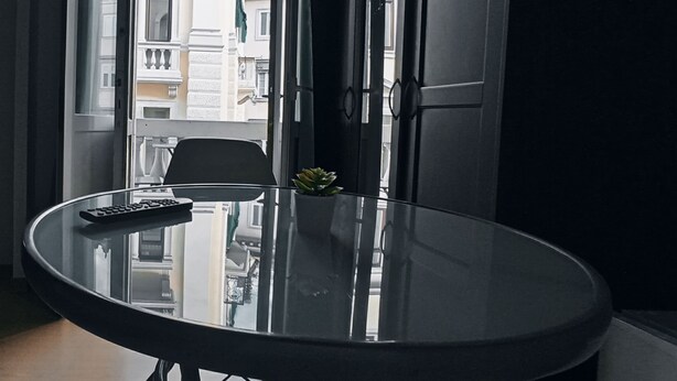 A room with a round glass table, a chair, and a potted plant. - Albergo N. Brioni (Trieste)