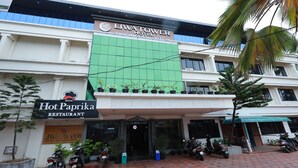 Un immeuble sur lequel on peut lire les inscriptions « Liwatower Hotel Business Center » et « Hot Paprika Restaurant ». Plusieurs motos sont garées devant.