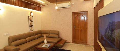 A living room with a sectional sofa, a coffee table, a TV, and a ceiling fan.
