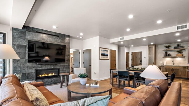 Ein modernes Wohnzimmer mit Kamin, Ledersofas, Essbereich und Küche.