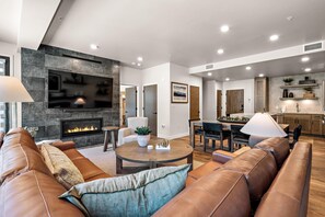 A modern living room with a fireplace, leather sofas, a dining area, and a kitchen. - Slope View Retreat | Includes Two 1-Day Lift Tickets (Donnelly)