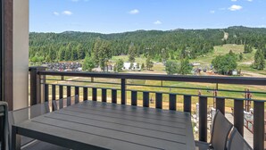 Ein Balkon mit Blick auf einen bewaldeten Hügel und einen Parkplatz.