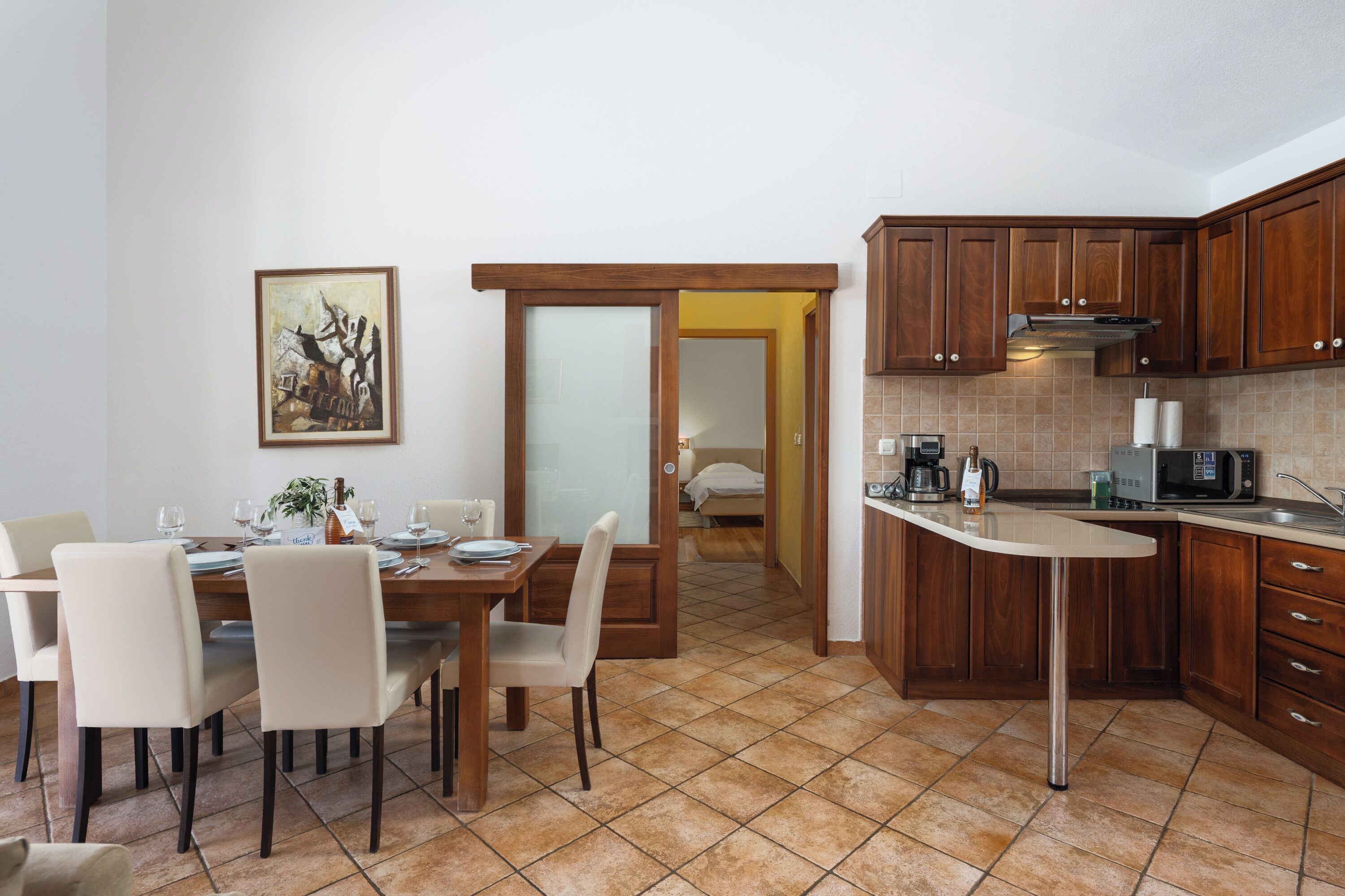 Una cocina moderna con armarios de madera, un comedor con mesa para cuatro y una isla de cocina.