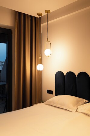 Habitación de hotel con cama, cortinas y lámparas colgantes.