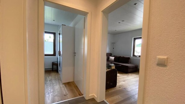 Corredor que leva a uma sala de estar com um sofá e uma mesa de centro.