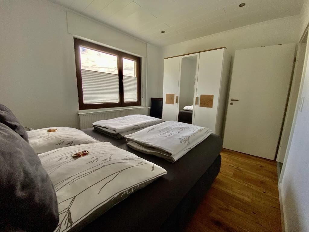 Een slaapkamer met twee bedden, een grote spiegel en een garderobe.