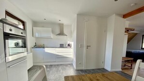 Una cocina moderna con armarios blancos, horno empotrado y una isla central.