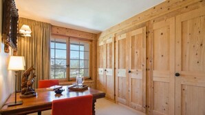 A wooden-paneled room with a dining table, chairs, and a window with curtains.
