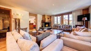 A spacious living room with a fireplace, comfortable seating, and large windows.