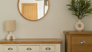 A wooden vanity with a mirror, a lamp, and a vase with green plants. - Squirrel Bank, with a hot tub & parking (Bowness-on-Windermere)
